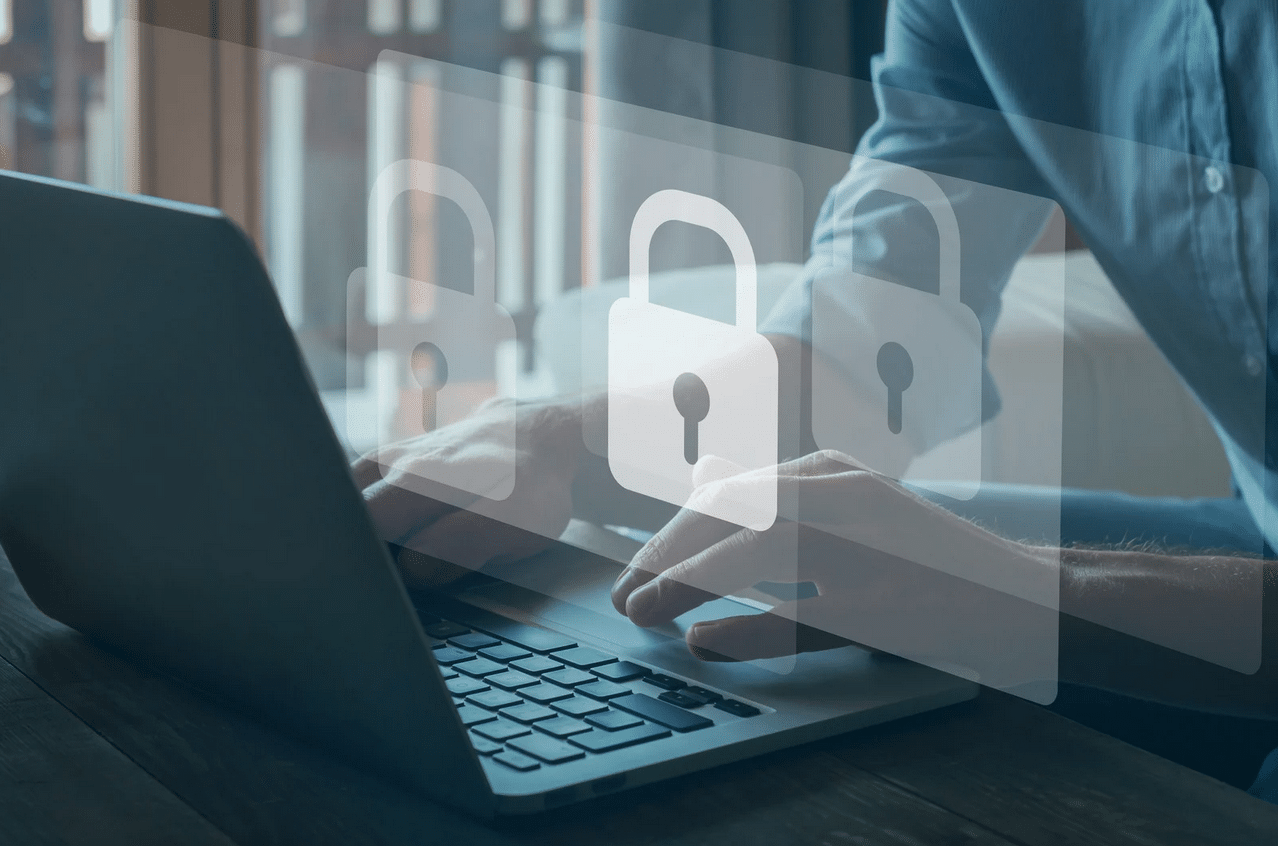 Person typing on a laptop with transparent padlock icons overlayed, representing cybersecurity or data protection concepts.
