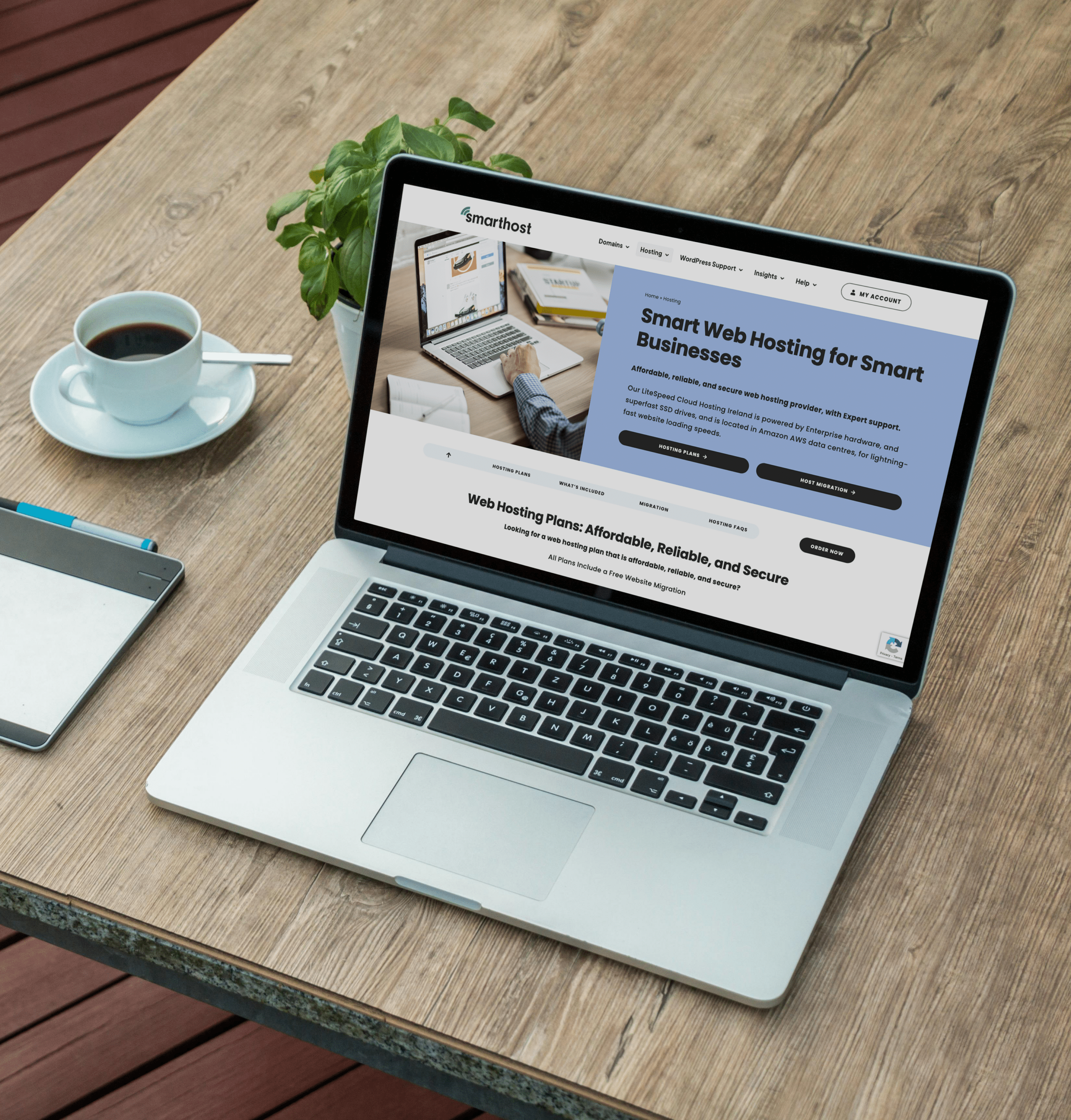 A laptop showcasing an Irish hosting provider website sits on a wooden table. Beside it, a notepad, pen, and steaming cup of coffee await your thoughts on hosting qualities.