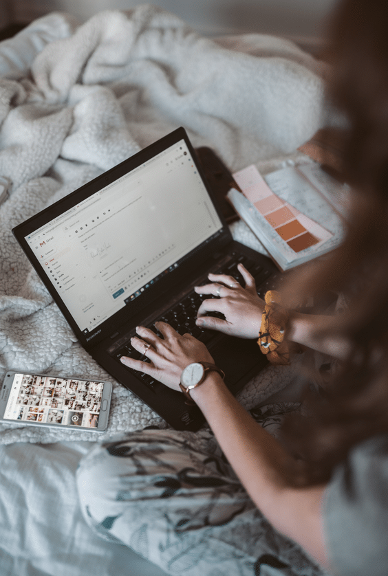 A woman browsing on a laptop in bed.