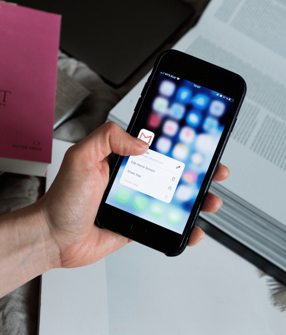 A hand holding a cell phone with a pink button on it based on Google's February 2024 Gmail Guidelines.