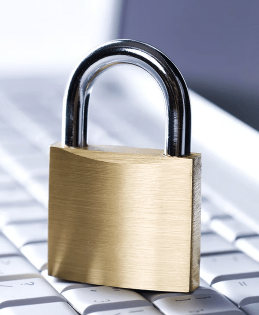 A brass padlock placed on a white computer keyboard.