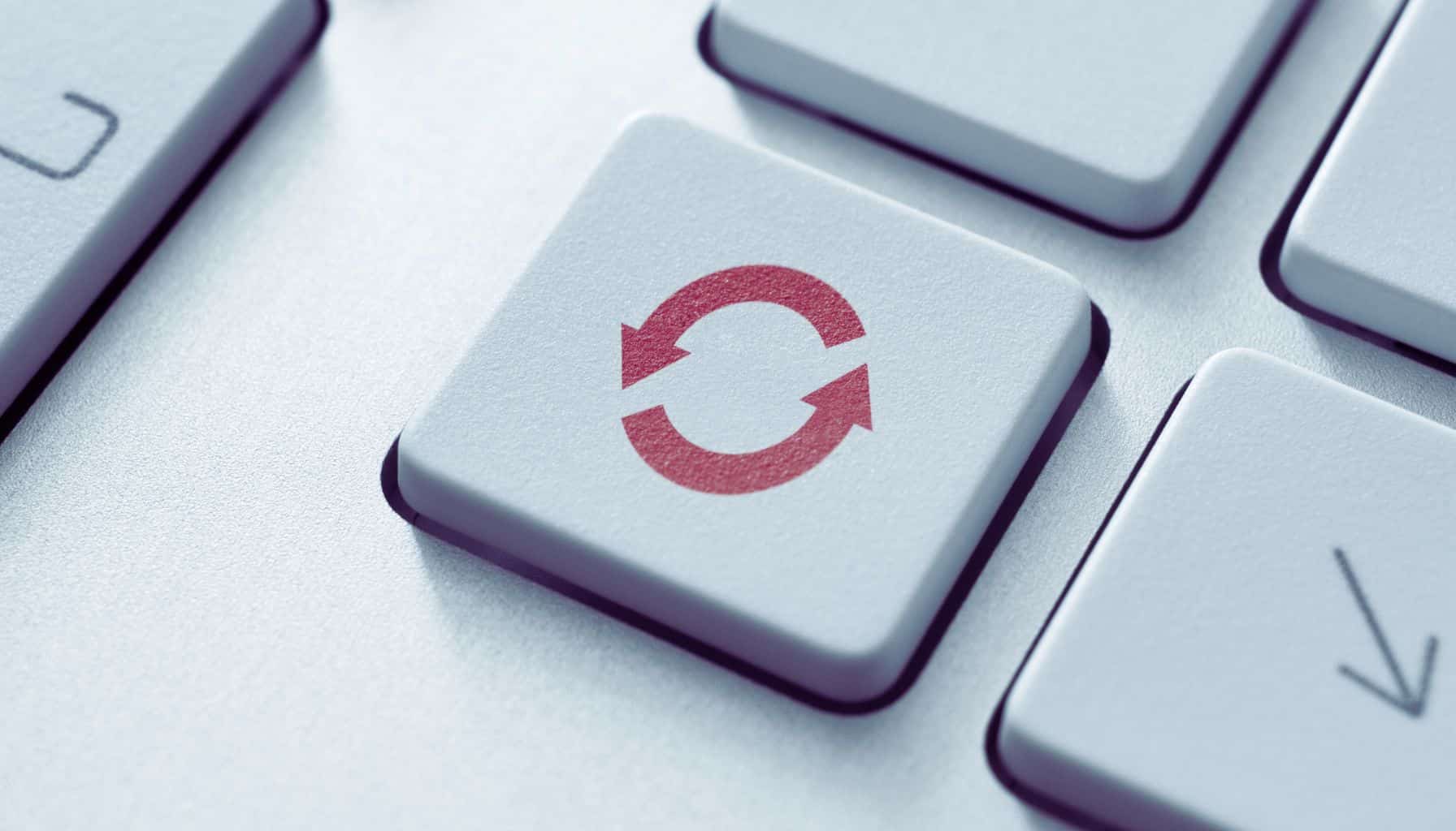 Close-up image of a keyboard, featuring a key with a red refresh symbol consisting of two circular arrows.