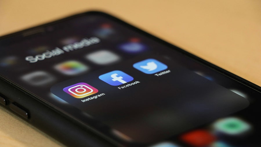 A smartphone displaying a folder labeled "Social Media" with the Instagram, Facebook, and Twitter app icons on the screen.