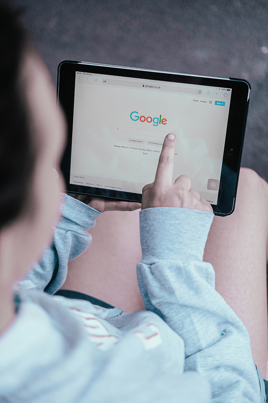 Person using a tablet to browse the Google homepage.