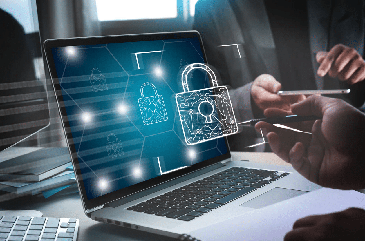 Laptop displaying digital padlock graphics, with two people in the background holding a tablet and a stylus, emphasizing cybersecurity and data protection.
