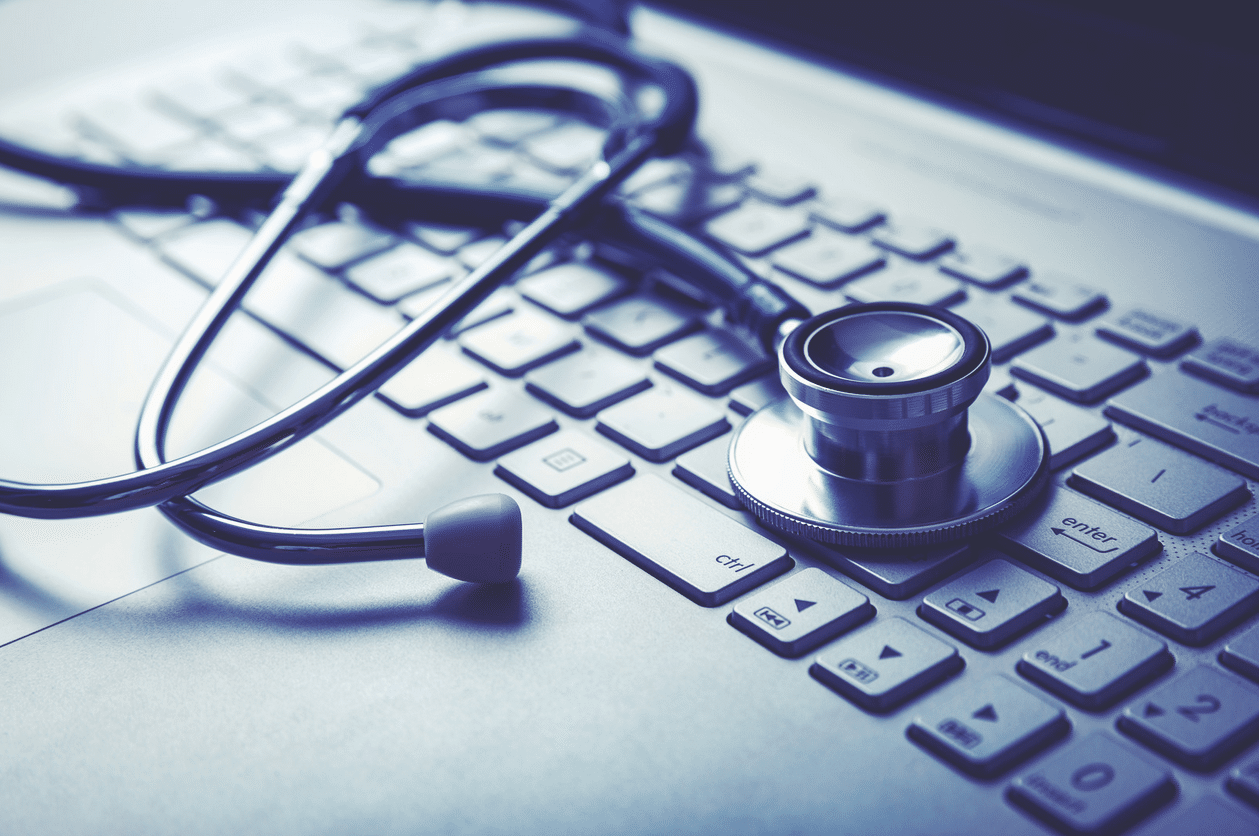 A stethoscope rests on a silver laptop keyboard.